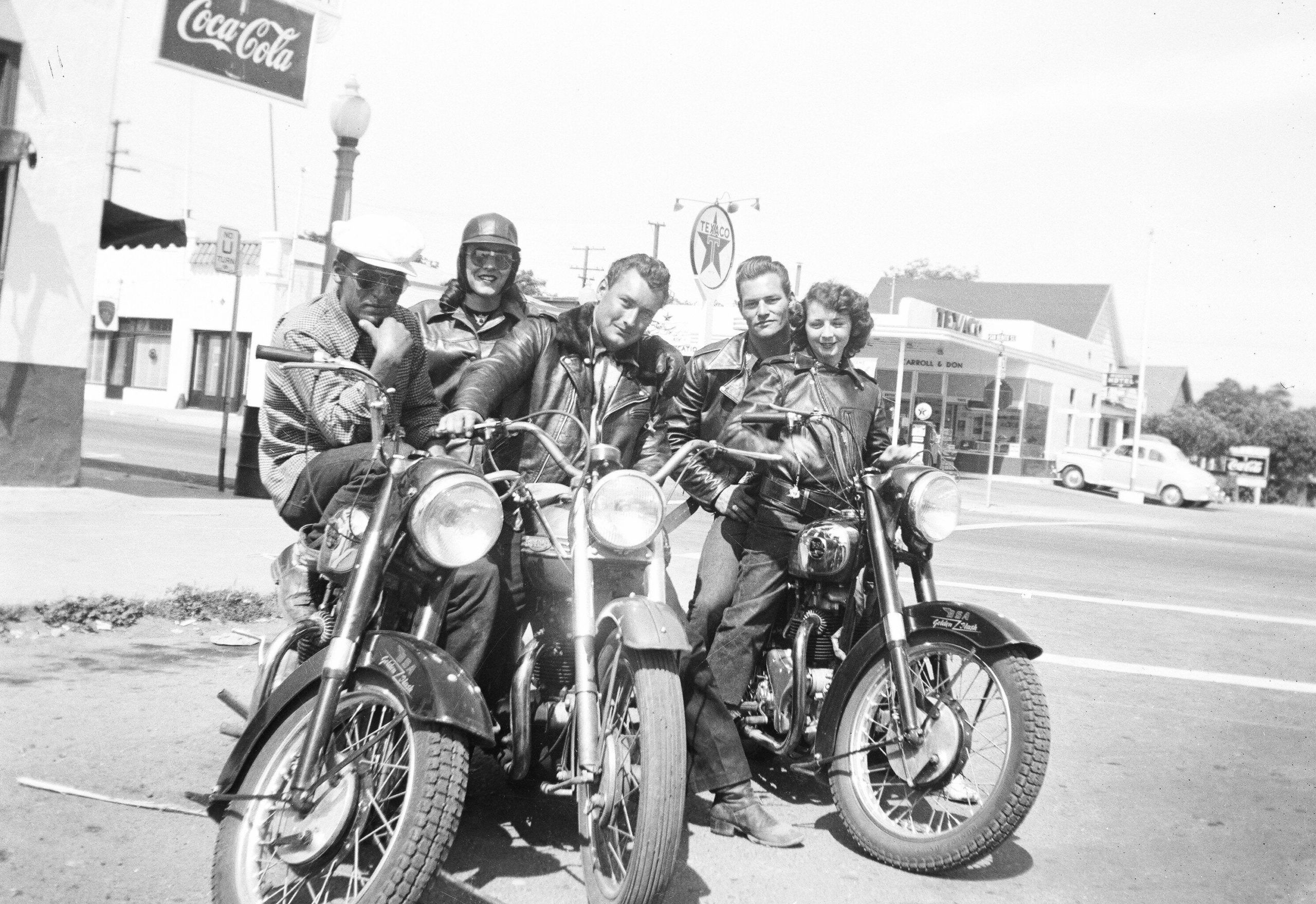Male and Female riders pose for a photo on a street in Hollister, CA. in July 1947