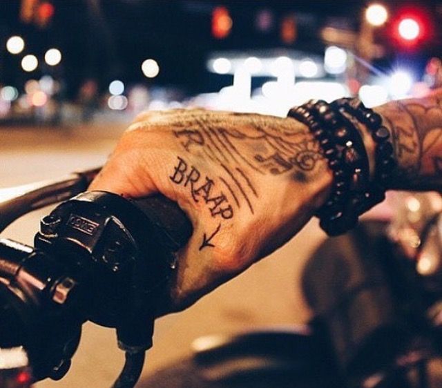 Close-up of motorcyclist's right hand with the words 'BRAAP' tattooed on it