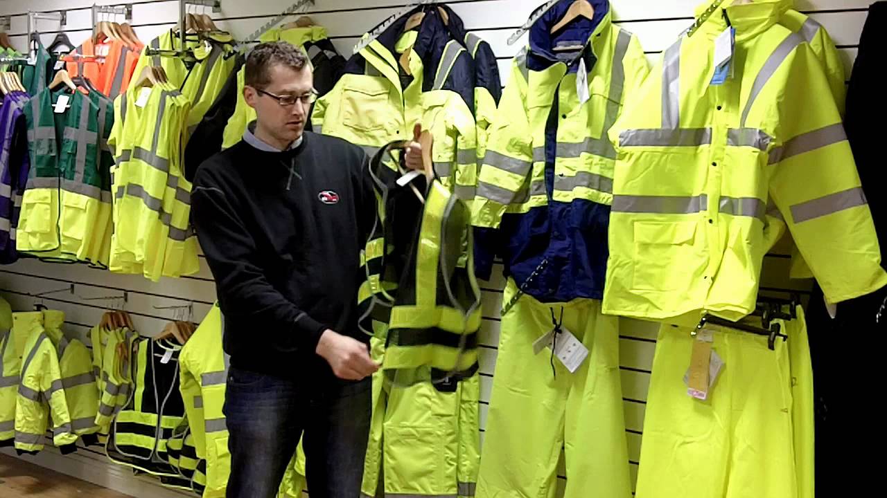 a French motorcycle store attendant hangs high viz gear on a rack